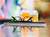 a book with eyeglasses resting atop it and glasses of beer in the background a book with eyeglasses resting atop it and glasses of beer in the background